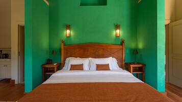 Una cama grande con cabecera de madera, dos mesitas de noche con lámparas y una pared verde.