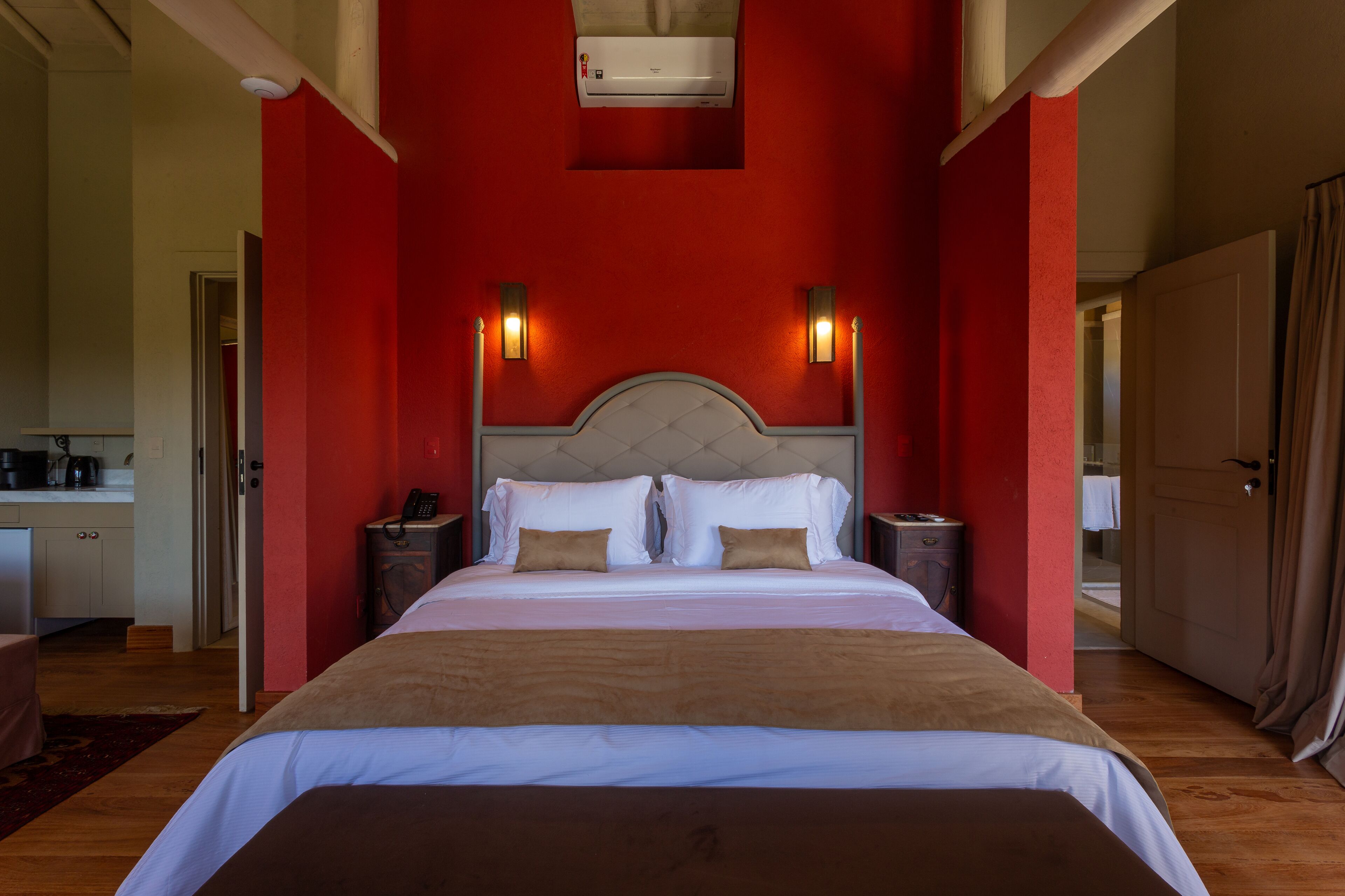 Una habitación de hotel con una cama grande, paredes rojas y dos lámparas de noche.