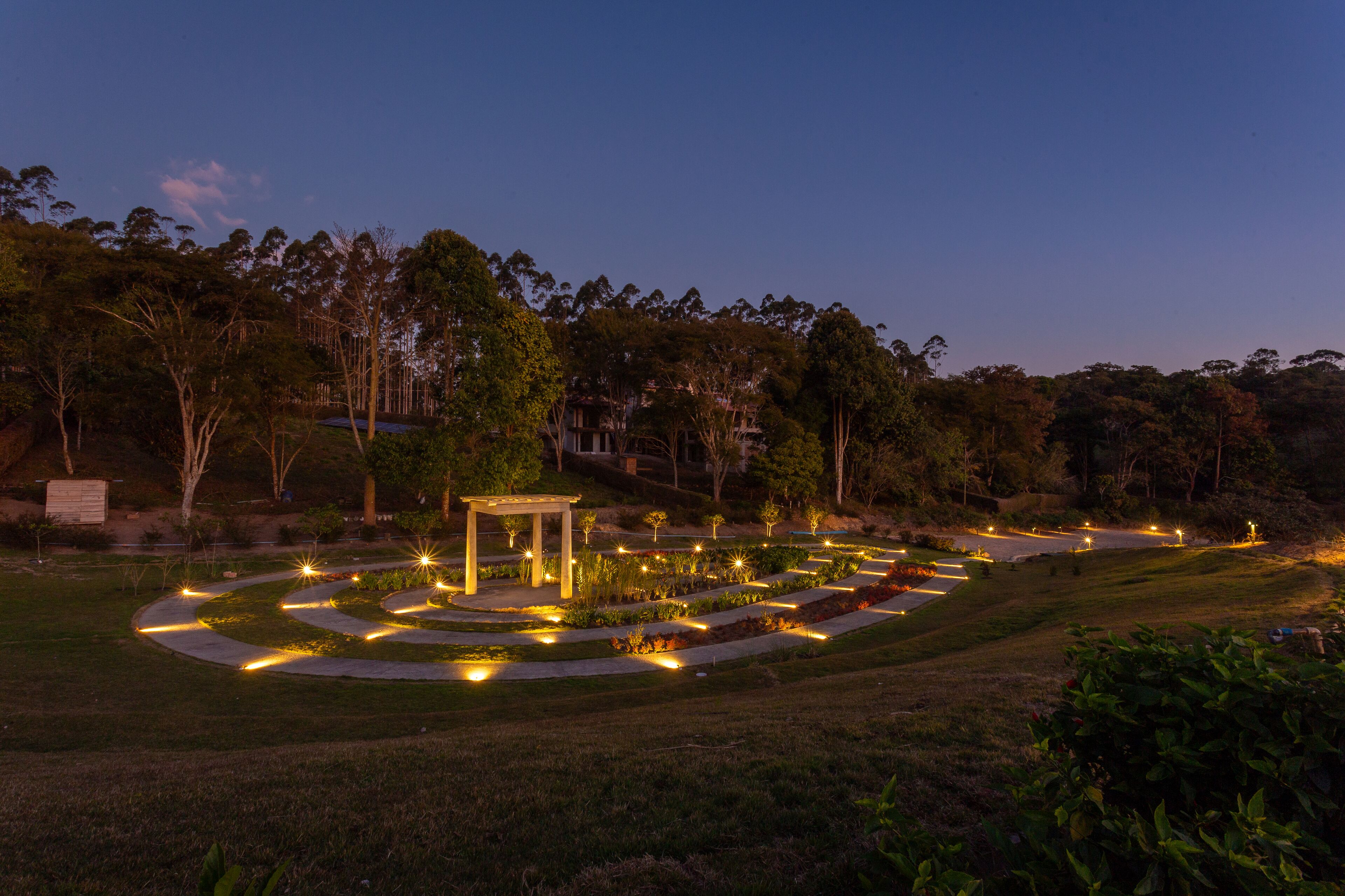 A landscaped garden with pathways, a gazebo, and surrounding trees.