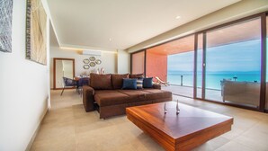 Un salon moderne avec un canapé marron, une table basse en bois et une vue sur la mer, visible à travers de grandes portes vitrées.