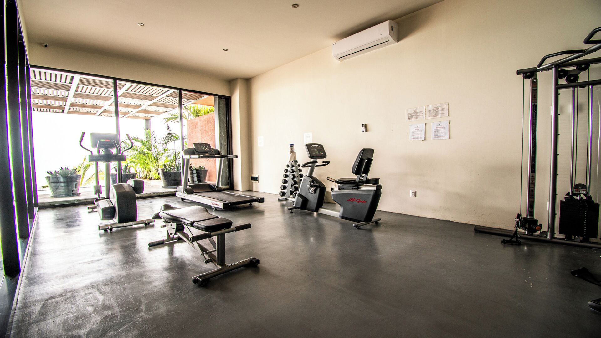 Un gimnasio con equipo de ejercicio diverso, incluyendo cintas de correr, máquinas de pesas y una máquina de remo.