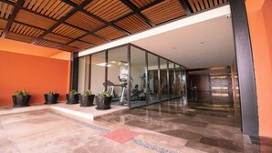 Un hall d’entrée moderne avec un mur en verre, des plantes en pot et un sol carrelé.