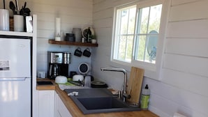 Een keuken met een houten aanrecht, een spoelbak, een koelkast en een raam.