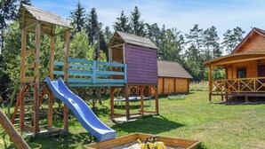 Une aire de jeux avec un toboggan, une structure d’escalade et un bac à sable rempli de jouets.
