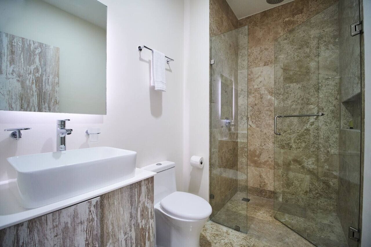 A bathroom with a white sink, toilet, and glass shower enclosure.