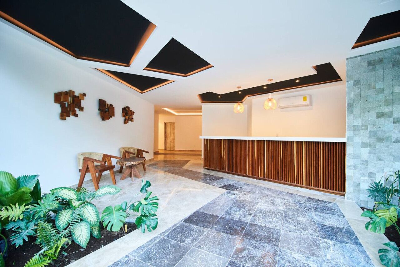 Una moderna recepción con un mostrador de madera, una zona de estar con sillones y un piso de baldosas.