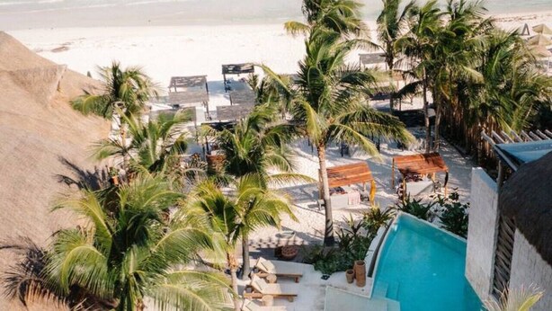 A resort with a pool, palm trees, and a beach view.