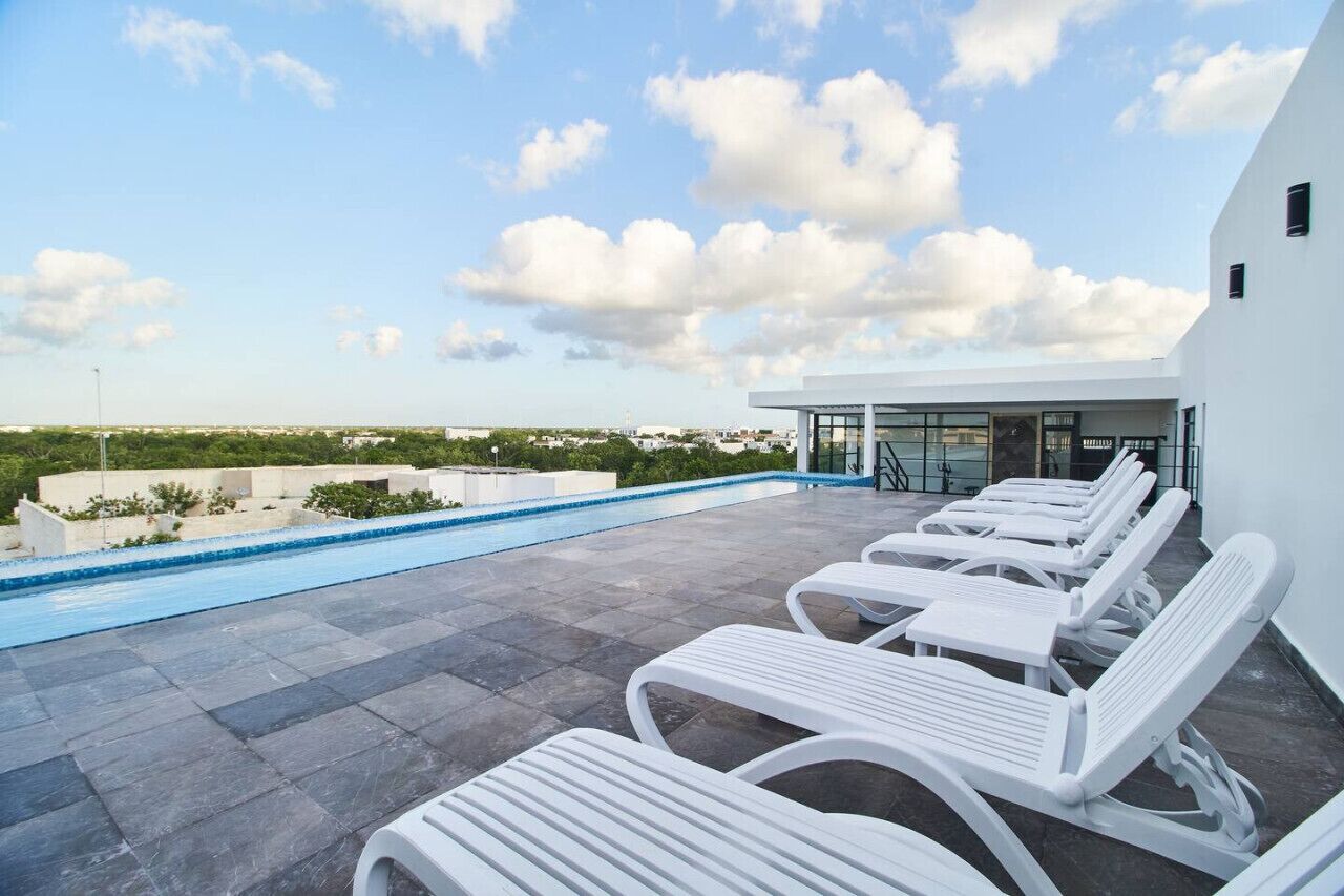 Un espace piscine aménagé sur le toit, avec des chaises longues et une vue dégagée sur les toits de la ville.