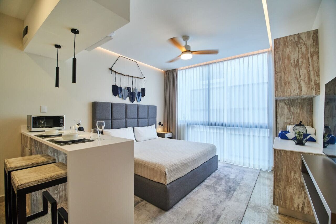 Une chambre d’hôtel moderne équipée d’un lit, d’un bureau, d’un four à micro-ondes et d’un ventilateur de plafond.