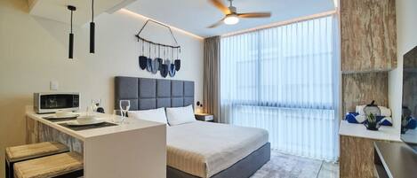 Une chambre d’hôtel moderne équipée d’un lit, d’un bureau, d’un four à micro-ondes et d’un ventilateur de plafond.