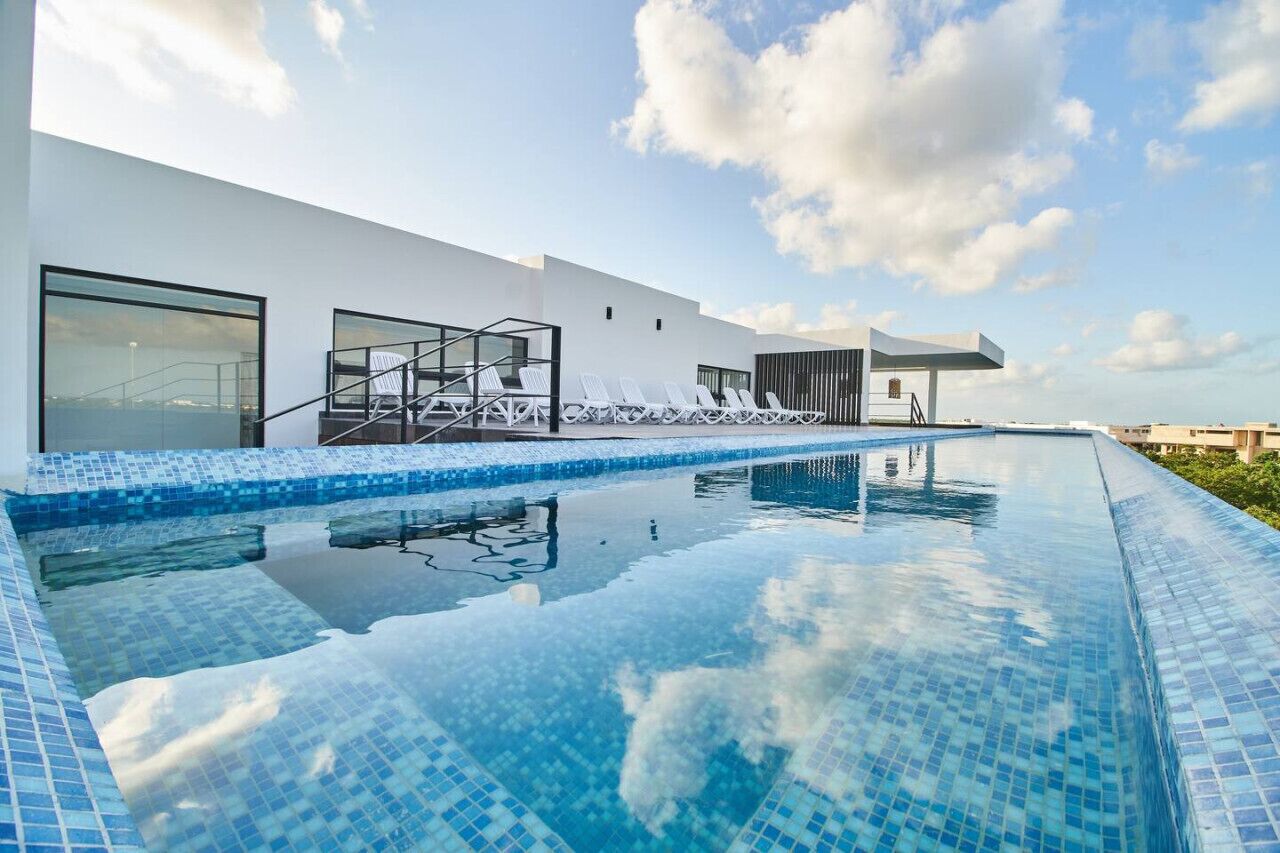 A modern building with a swimming pool, large windows, and a clear sky.