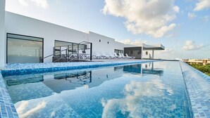 A modern building with a swimming pool, large windows, and a clear sky.