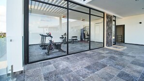 A modern interior with a glass wall, exercise equipment, and a tiled floor.