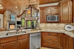 A kitchen with wooden cabinets, a granite countertop, a built-in microwave, and a stone fireplace. - Lake Overlook: Buckeye Lake views, Mtn views, high elevation arcade games, ping pong, fireplace (Banner Elk)