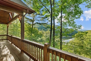 A wooden deck with a railing overlooking a forested valley and a lake. - Lake Overlook: Buckeye Lake views, Mtn views, high elevation arcade games, ping pong, fireplace (Banner Elk)