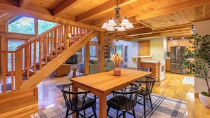 Un interior espacioso de madera con comedor, cocina y escalera.