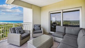 A balcony with wicker furniture, a sofa, and a view of the ocean.