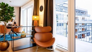 Una sala de estar moderna con un ventanal grande, un comedor y vistas a un paisaje urbano.