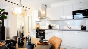 Una cocina moderna con armarios blancos, una estufa de acero inoxidable y un microondas negro.