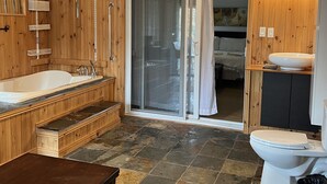Een houten interieur met een bad, toilet en een douche.