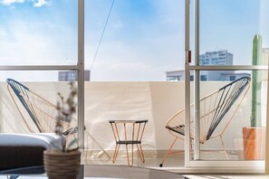 Relax in a spacious room with a city view, featuring a comfortable seating area and large window.