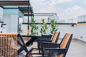 Relax in a rooftop seating area with wicker and metal furniture, perfect for casual dining or meetings.