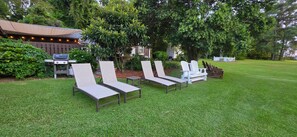 A grassy outdoor area with lounge chairs and a barbecue grill. - The Elderberry Studio (Wanchese)