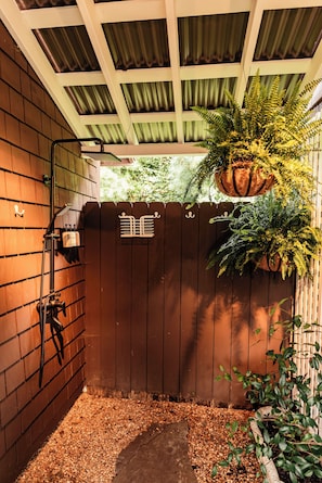 A wooden gate with a metal lock, a potted plant, and a small pathway leading to a covered area with a ceiling. - Waterfront, Studio and Gardens, Huge grass lawn, Dogs Ok, with fee (Wanchese)