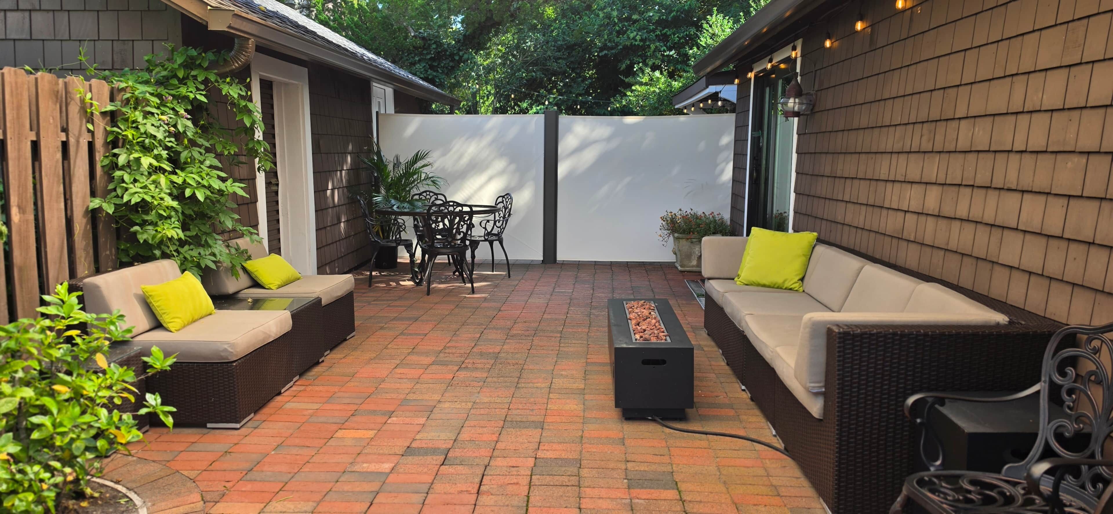 Een terras met buitenmeubilair, een tafel en een vuurplaats.