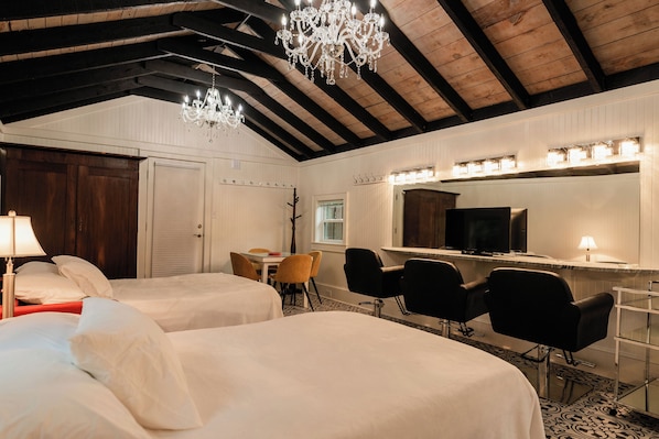 A hotel room with two beds, a desk, chairs, a chandelier, a television, and a mirror. - Waterfront, Studio and Gardens, Huge grass lawn, Dogs Ok, with fee (Wanchese)