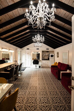 A spacious room with a high ceiling, a chandelier, a dining area with a long table and chairs, and a patterned floor. - The Elderberry Studio (Wanchese)