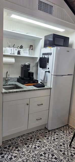A compact kitchen with a built-in microwave, a coffee maker, and a refrigerator. - The Elderberry Studio/Check Availability for discounted rates Code: FALL26 (Wanchese)