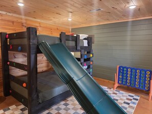 Una cama litera con tobogán, pared de escalar y pared de escalar para juguetes.