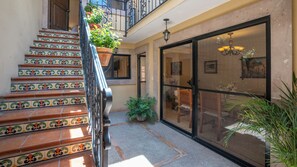 A staircase with colorful tiles, a glass door leading to an interior space, and a balcony with plants.