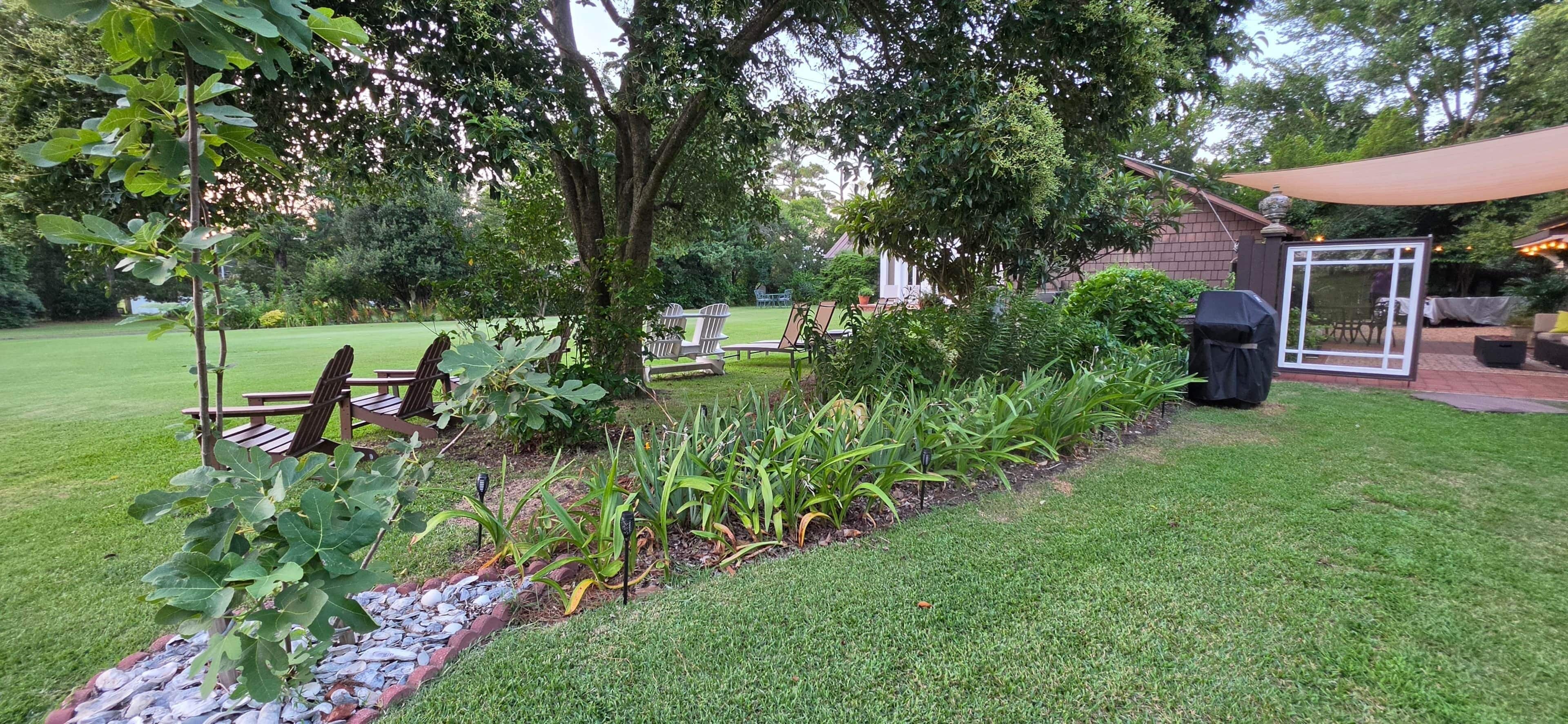 A well-maintained garden with a patio area, outdoor seating, and a barbecue setup.