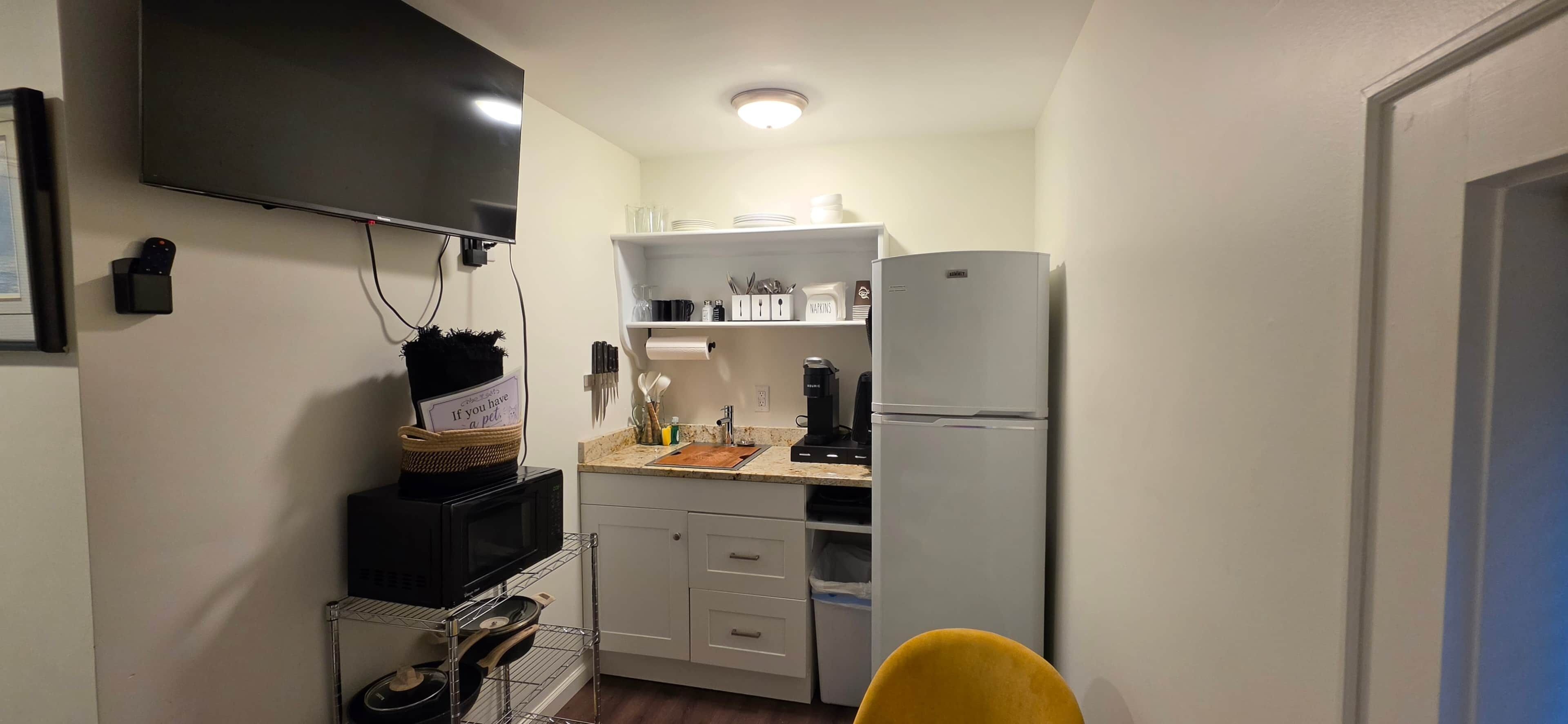 Une cuisine compacte équipée d’un four à micro-ondes, d’une machine à café et d’un réfrigérateur.