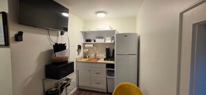 A compact kitchen with a microwave, coffee maker, and a refrigerator. - The Jasmine Bunkhouse (Wanchese)