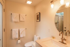 A bathroom with a toilet, sink, and two towels hanging on the wall.
