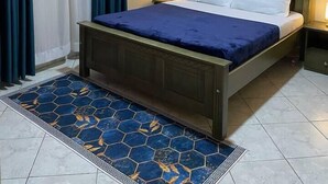 Ein Hotelzimmer mit einem Bett, einem Nachttisch, einer Wandlampe und einem Teppich.