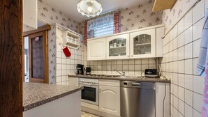 A kitchen with white cabinets, a dishwasher, an oven, and a coffee maker. - Apartment 'Ferienwohnung Im Harz' with Wi-Fi (Harzgerode)