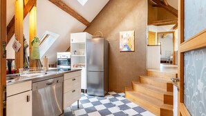 A kitchen with a stainless steel refrigerator, wooden cabinets, a checkered floor, and a staircase leading to another room. - Holiday Apartment Wegwarte with Mountain View, Shared Terrace and Wi-Fi (Weilheim)