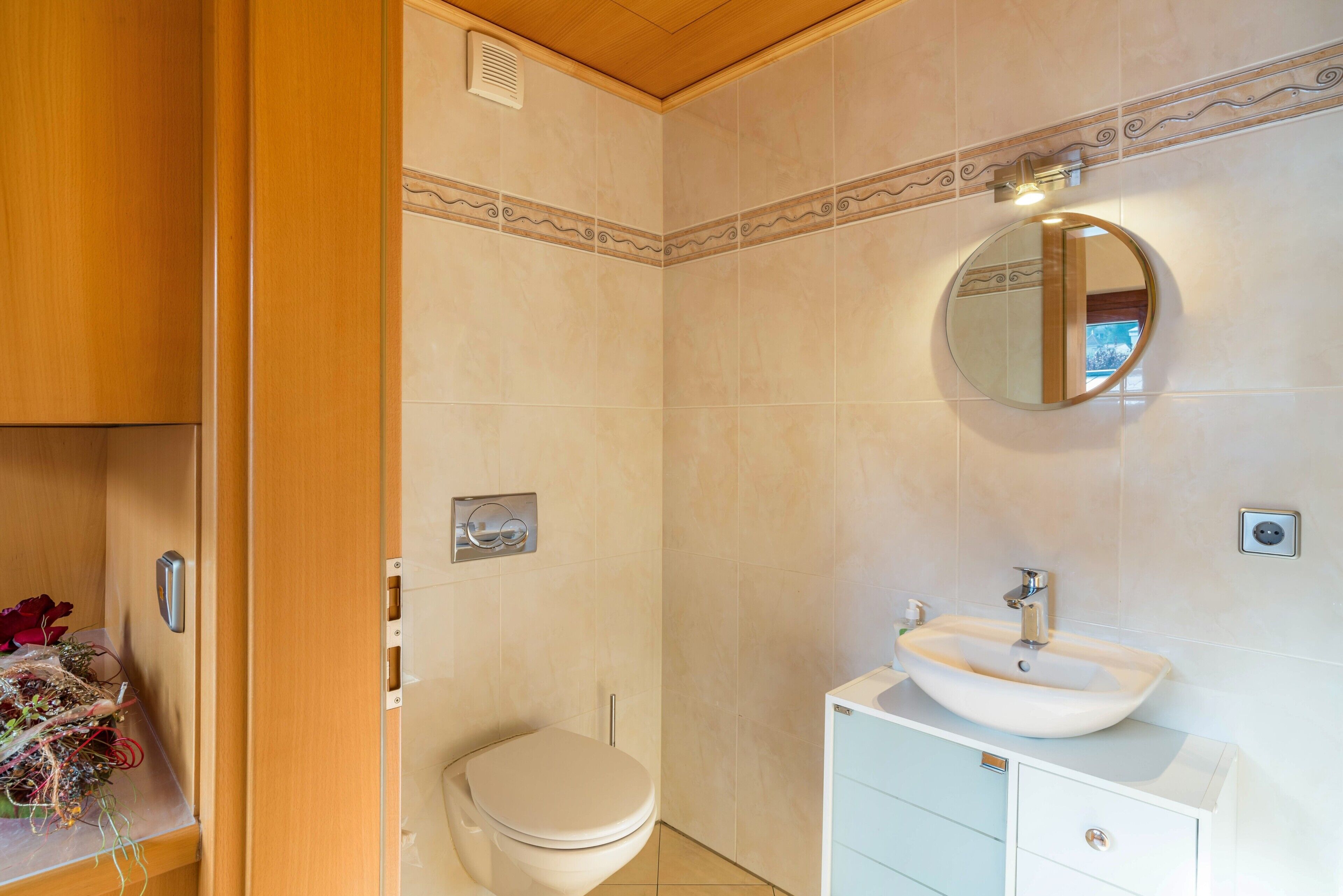 Een badkamer met toilet, wastafel, spiegel en een houten kastje.