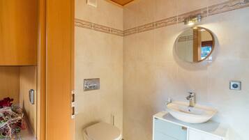 Een badkamer met toilet, wastafel, spiegel en een houten kastje.