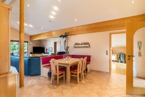 A dining area with a wooden table and chairs, a red bench, and a television in the background. - Holiday Apartment 'Haus Am Bächel' with Balcony and Wi-Fi (Lauf)