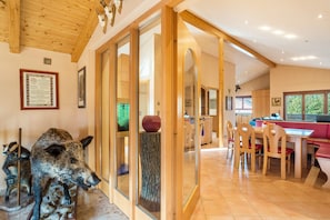 A dining area with wooden chairs and a table, a glass partition, and a mounted animal head. - Holiday Apartment 'Haus Am Bächel' with Balcony and Wi-Fi (Lauf)