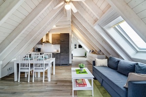 Un loft moderno con zona pranzo, cucina e angolo living, caratterizzato da travi in legno e lucernari.