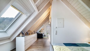 A modern loft bedroom with a skylight, built-in bench, and a view of the outdoors.