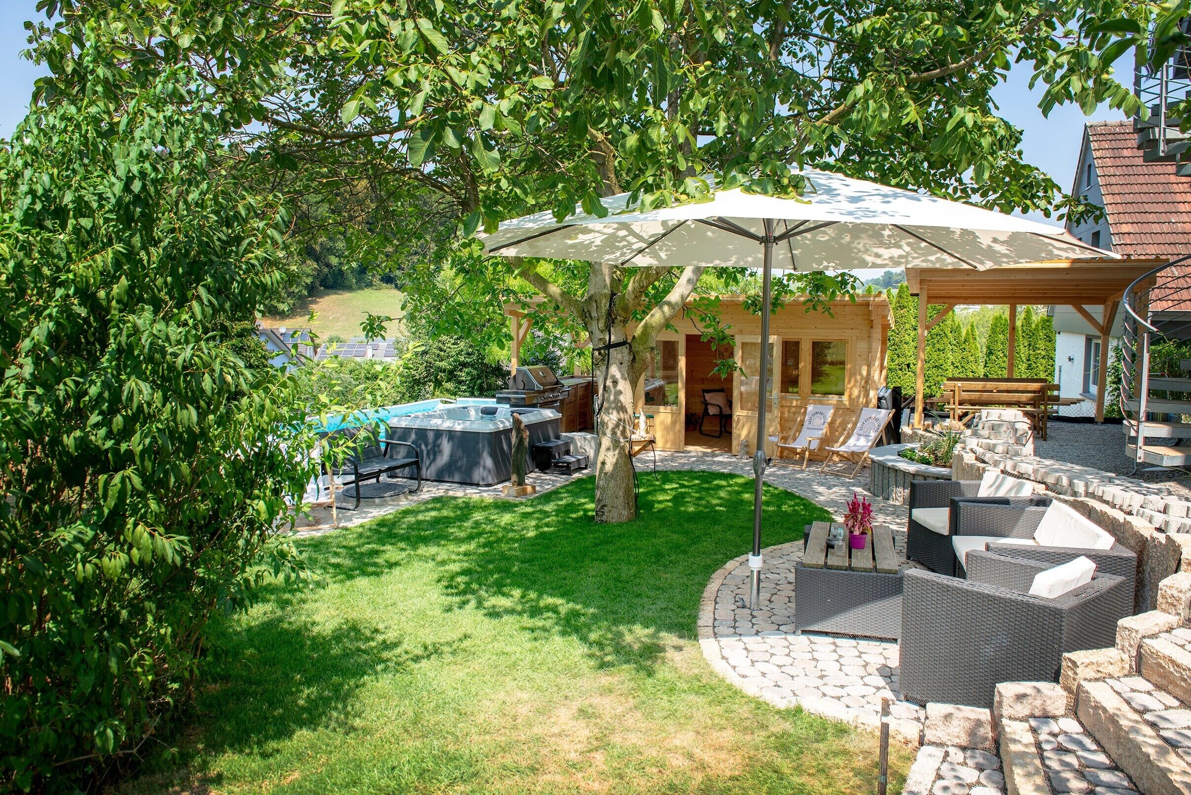 A backyard with a barbecue area, outdoor seating, and a hot tub.