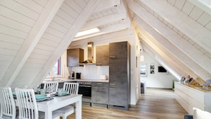 A modern kitchen with a dining area, wooden beams, and a view of the city.