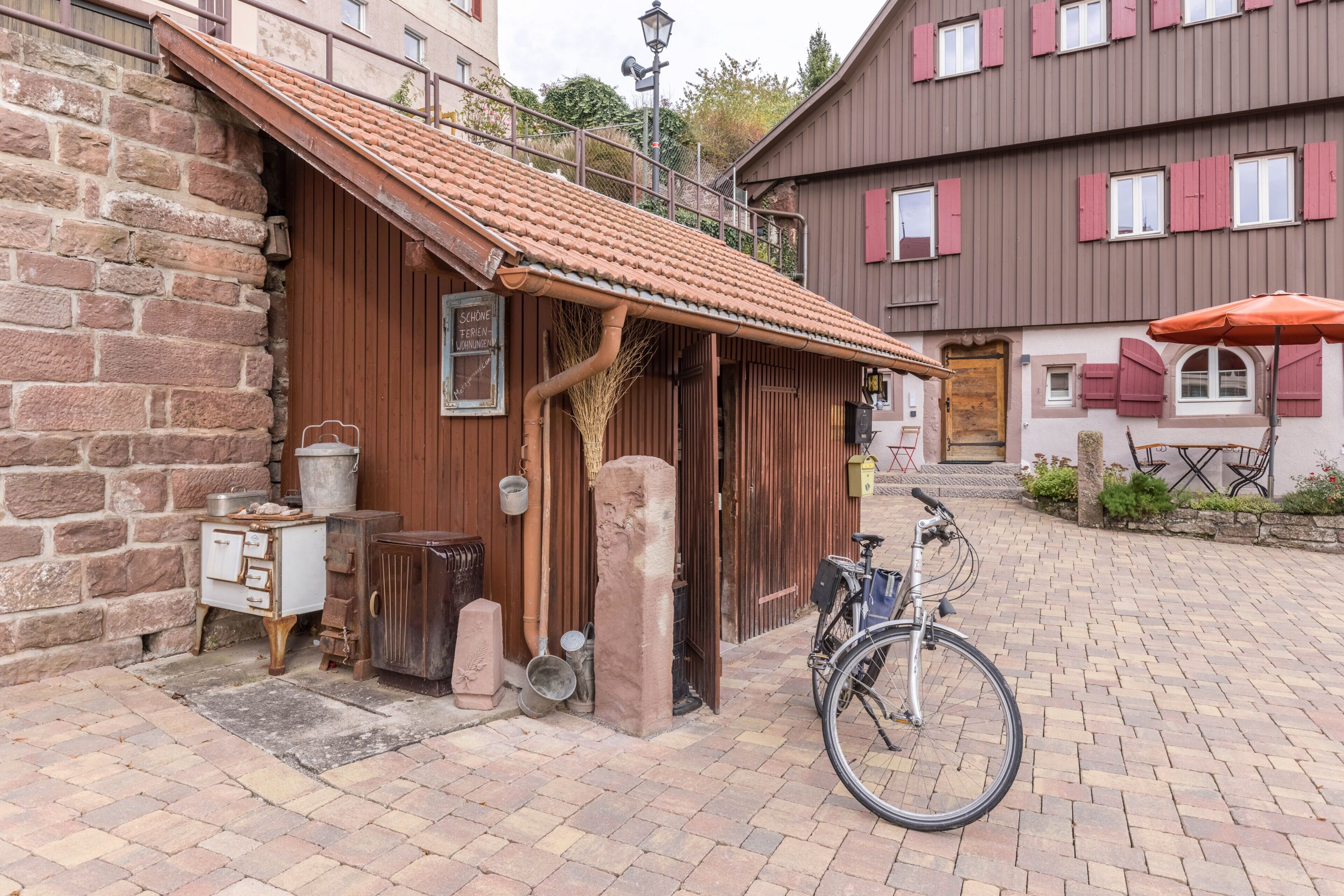 A rustic building with a tiled roof, a bicycle, and a wooden bench outside.